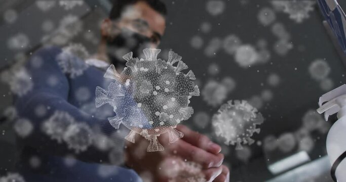 Animation of covid-19 cells over middle eastern man wearing face mask applying hand sanitizer