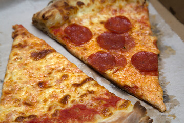 new york city style pizza slice (pepperoni, plain slice) nyc pizzeria with crushed red pepper flakes on greasy parchment paper, cardboard box