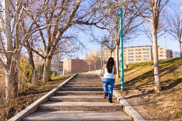 Fototapeta na wymiar Young woman climbing stairs in a park