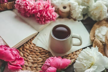 Beautiful spring composition, good morning concept. Cup of tea, peonies and open book