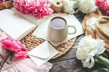 Beautiful spring composition, good morning concept. Cup of tea, peonies and open book