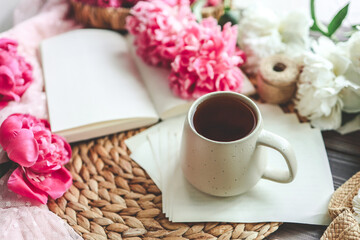 Beautiful spring composition, good morning concept. Cup of tea, peonies and open book