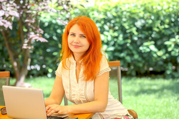 The girl works behind a laptop in a summer cafe on the street. Summer. business concept