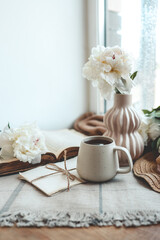Fototapeta na wymiar Cup of tea, straw hat, open book and peonies, spring still life