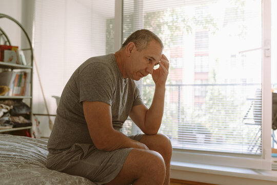 Middle-aged man in bedroom sitting on bed
