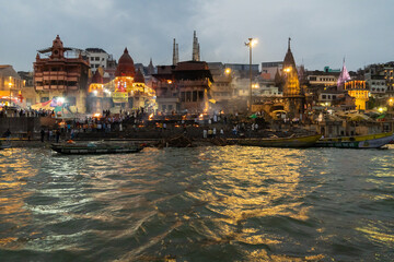 India Varanasi ganga ghat at night, view of the crowded banks of people and funeral pyres - obrazy, fototapety, plakaty