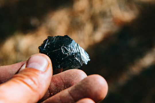 A hand holds a chip of black obsidian in the Valles Caldera National Preserve, New Mexico