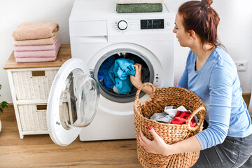 Woman using washing machine with clothes detail.