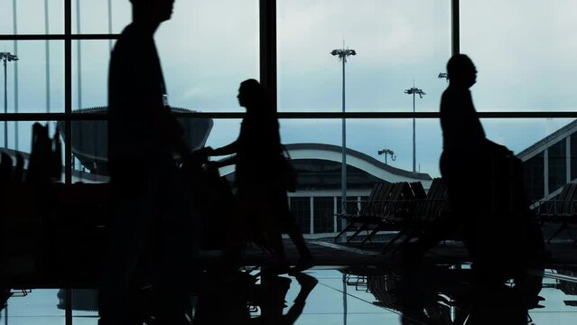 Silhouettes and reflections of passenger waiting and walking in airport.