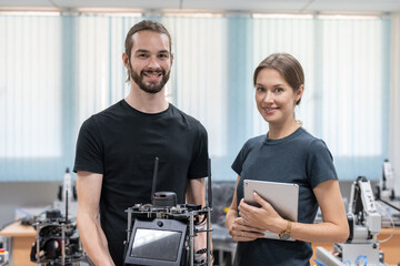 Portrait of male and female engineers researchers testing and controlling AI robot at academy...