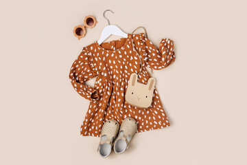 Stylish kids dress with cute handbag and shoes on a hanger on a beige background. Fashion kids...