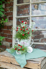 Natürlicher Blumenstrauß in alter Kaffeekanne, rustikale Tischdekoration, frische Blumen, roter Kugelamaranth, Schleierkraut