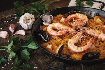 spanish seafood paella with prawns and mussels, traditional dish with rice, hot pot, surrounded by fresh ingredients on a rustic wooden table