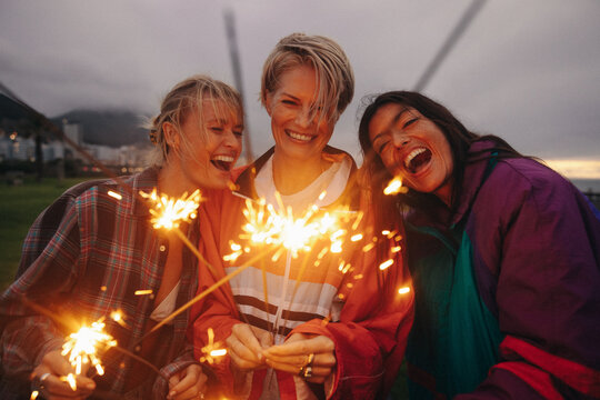 Friends celebrating outdoors with sparklers and bengal lights
