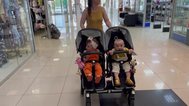 mother with two twins in the mall. mom with a stroller with baby twins walks along the supermarket. happy family kid dream concept. mother and baby twins with a stroller in lifestyle the mall