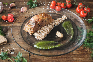 chicken fillet with rice, vegetables and sauce served on a glass plate on wooden rustic table, fresh ingredients on the table