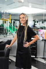 happy hairdresser, woman with braids in beauty salon, hair extension, beauty worker, salon work, hair trends, positivity, interior, profession, salon industry, professional headshots