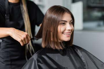 client satisfaction, cheerful woman with short brunette hair sitting in hairdressing cape in beauty...