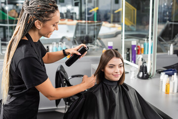 salon services, hair spray, happy hairdresser with braids styling hair of female customer, happy brunette woman with short hair, beauty salon, hair volume, hair professional, hairdressing cape