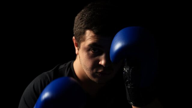Male fighter boxing in the dark, training routine, getting ready for a fight 