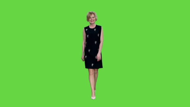 Smiling adult woman in dress walking on green background, Front view, Chroma key, 4k pre-keyed footage