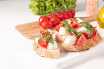 Tomato, basil and cheese fresh made caprese bruschetta. Italian tapas, antipasti with vegetables, herbs and oil on grilled ciabatta and baguette bread. Sandwich.