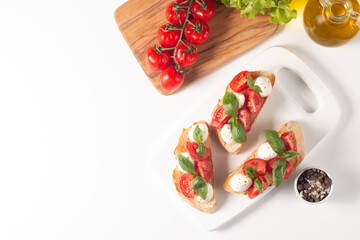 Tomato, basil and cheese fresh made caprese bruschetta. Italian tapas, antipasti with vegetables, herbs and oil on grilled ciabatta and baguette bread. Sandwich.