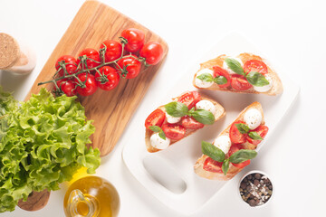 Tomato, basil and cheese fresh made caprese bruschetta. Italian tapas, antipasti with vegetables, herbs and oil on grilled ciabatta and baguette bread. Sandwich.