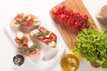 Tomato, basil and cheese fresh made caprese bruschetta. Italian tapas, antipasti with vegetables, herbs and oil on grilled ciabatta and baguette bread. Sandwich.