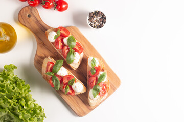 Tomato, basil and cheese fresh made caprese bruschetta. Italian tapas, antipasti with vegetables, herbs and oil on grilled ciabatta and baguette bread. Sandwich.