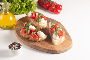 Tomato, basil and cheese fresh made caprese bruschetta. Italian tapas, antipasti with vegetables, herbs and oil on grilled ciabatta and baguette bread. Sandwich.