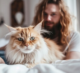 Close up of a cute shaggy cat and happy smiling man on the bed