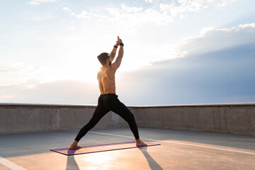 attractive hansome man with athletic strong body doing morning yoga asana outdoors