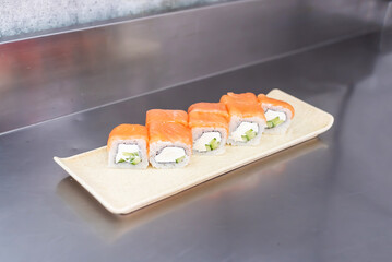 Sushi roll with salmon, cheese and cucumber on a white board