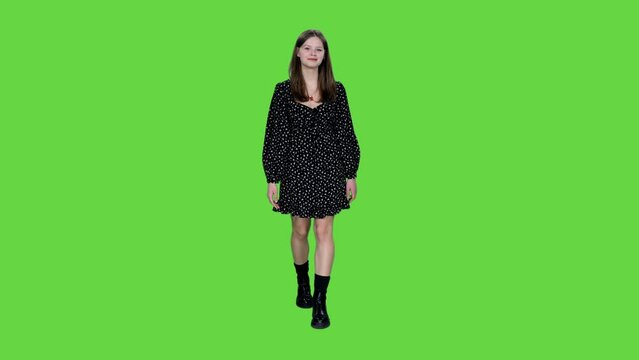 Young stylish smiling woman walking in short polka dot dress and black high-soled boots on green background, Chroma key, 4k pre-keyed footage