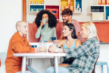 young people in youth hostel kitchen relaxing and chatting together