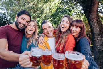 smiling friends having fun outdoors cheering with a pint of beer