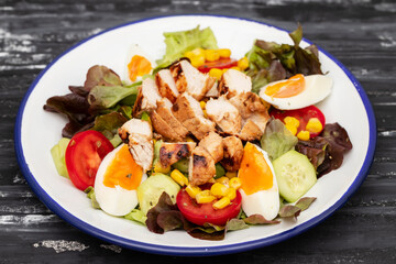 Delicious light vegetable salad made from tomatoes, canned corn, cucumber, lettuce, avocado, boiled egg and chicken