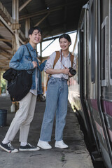 Fototapeta na wymiar Couple Young asian traveler tourist by train Choose a trip and booking train queue by smartphone. Two Backpacker at platform train station. Happy traveller at railway on vacation holiday weekend.