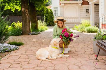 Fototapeta premium beautiful young woman in summer style outfit smiling happy walking with flowers and dog