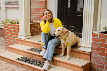 happy smiling woman in yellow sweater walking at her house with a dog golden retriever