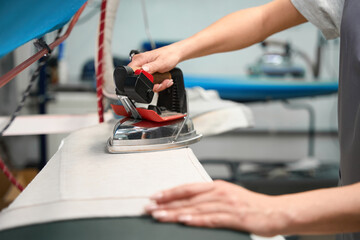 Laundry service worker carefully ironing clothes to get rid of wrinkles
