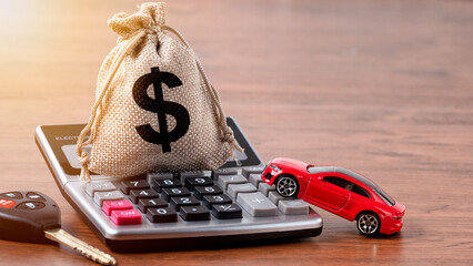 Money bag on calculator with car key and red car in background. Buying new car or car loan concept.