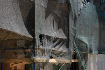 Building facade cover during repair works, scaffolding on site covered with  net