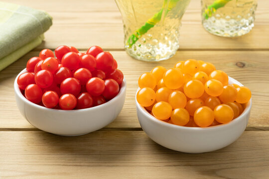 Pair of bowls with fresh red and yellow Tomberry tomatoes close up