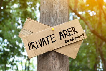Private Area on paper signpost sticked on tree in the public park to warn people to avoid walking or entering into this area and not arrow to stay in this area, soft and selective focus.