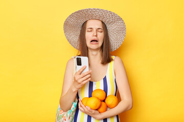 Crying sad unhappy woman wearing striped one-piece swimsuit and straw hat posing isolated over...