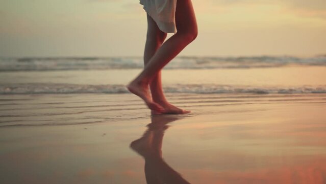 B roll - Woman feet walking along sea water waves on sandy beach in sunset, Female tourist on summer travel vacation, Slow motion