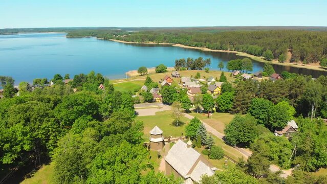 Aerial panning view beautiful iconic St.Joseph wooden stave church with no nails in famous Lithuania countryside holiday Village Paluse with Lusiai lake panorama in summer