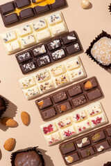 Craft white, milk and black chocolate candies on beige background flat lay, top view